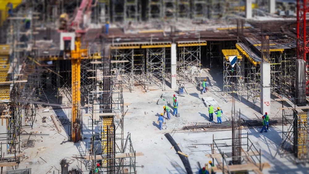 Workers build a structure while Ozark Grease Pros ensures safe grease disposal nearby for proper site management.